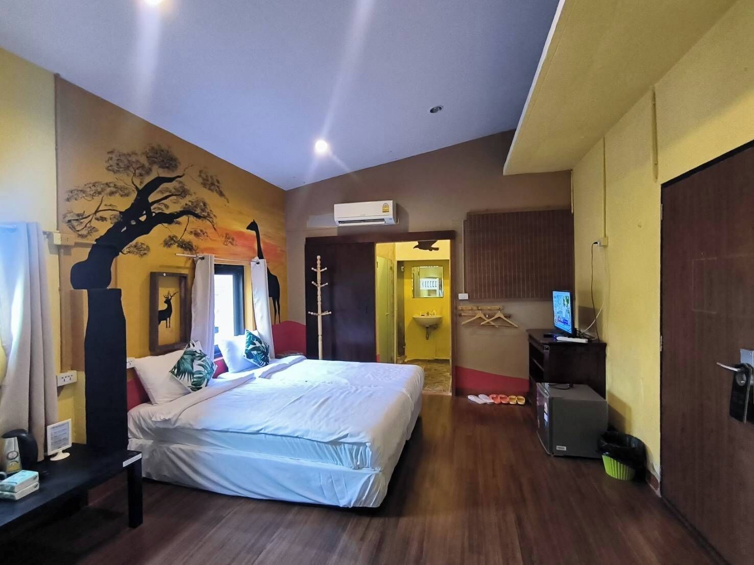 Una habitación de hotel con cama, escritorio, televisión y baño visible a través de una puerta abierta.