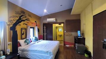 Una habitación de hotel con cama, escritorio, televisión y baño visible a través de una puerta abierta.