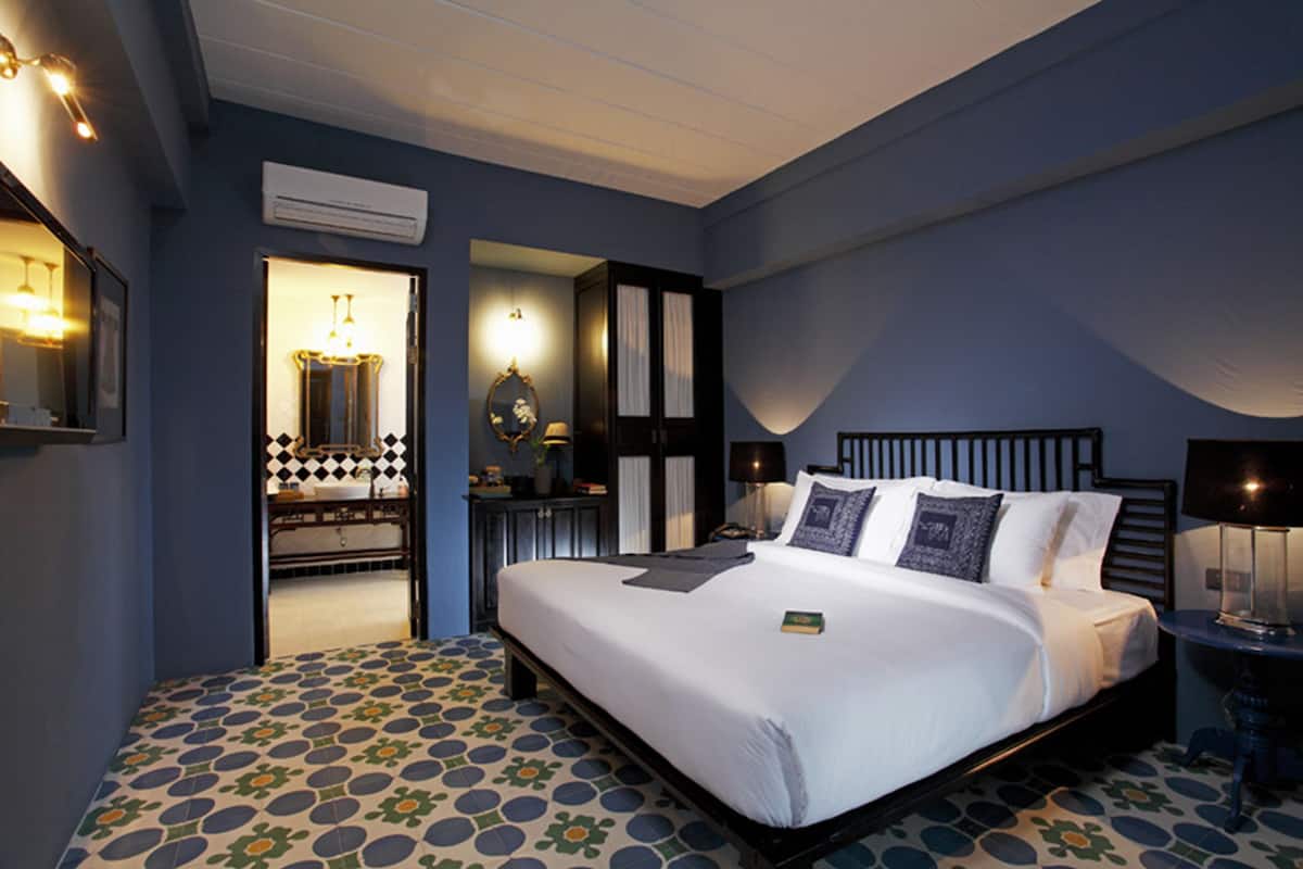 A bedroom with a large bed, a nightstand, a mirror, and a door leading to a bathroom.