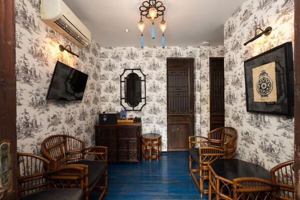 Una habitación con papel tapiz tradicional chino, una mesa negra y sillas de madera.