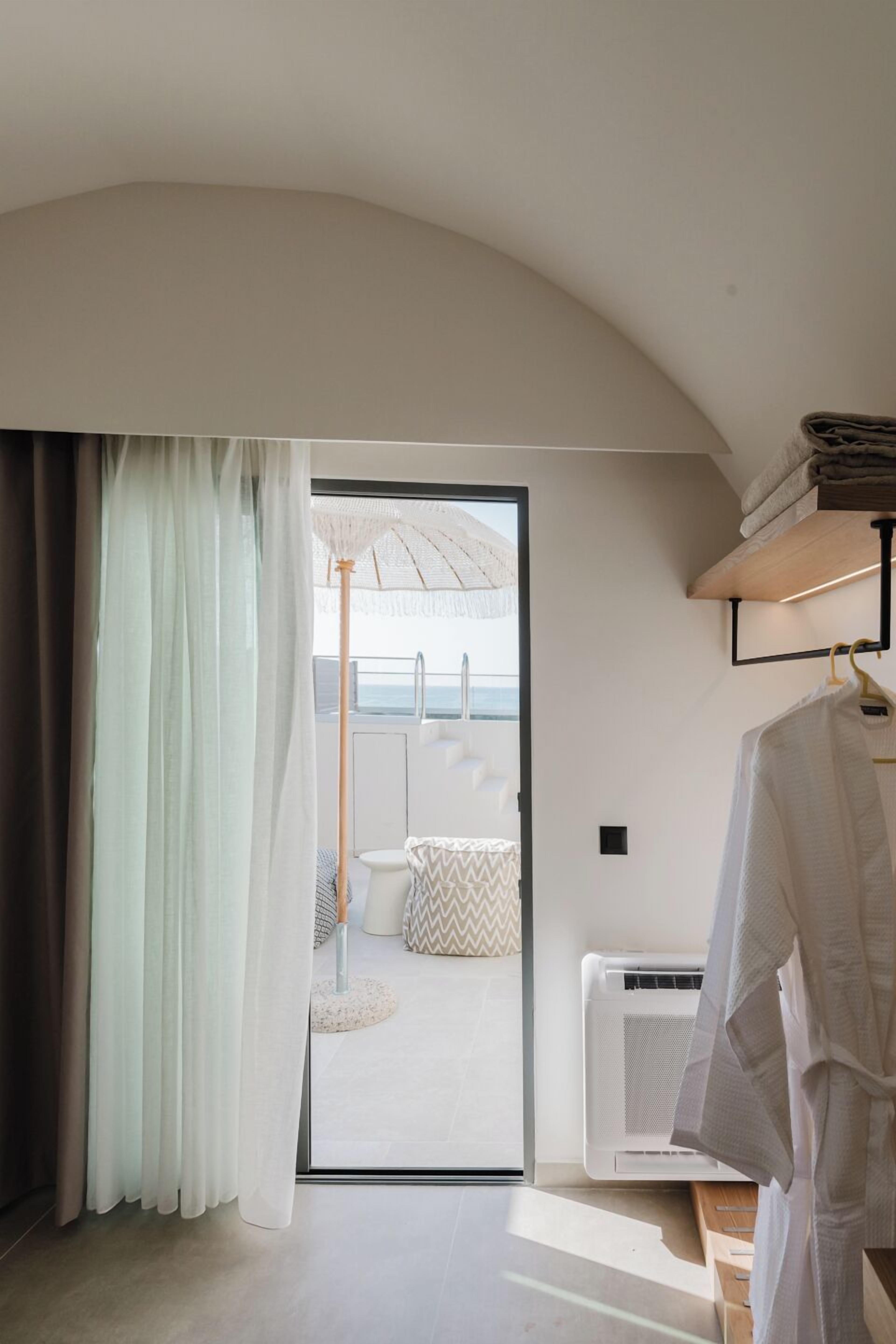 A modern room with a sliding glass door leading to a balcony with a beach view.