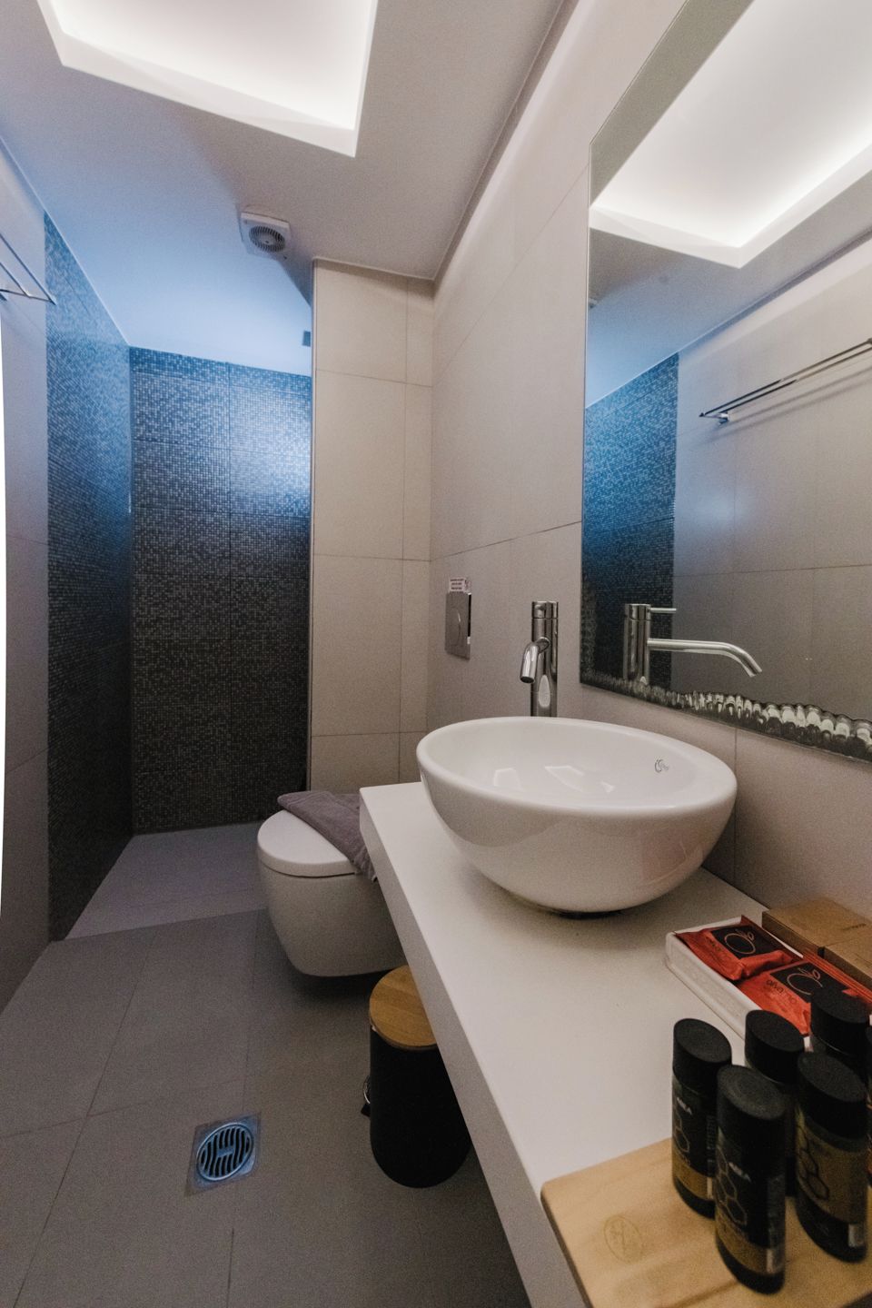 A modern bathroom with a white sink, a large mirror, and a shower area.