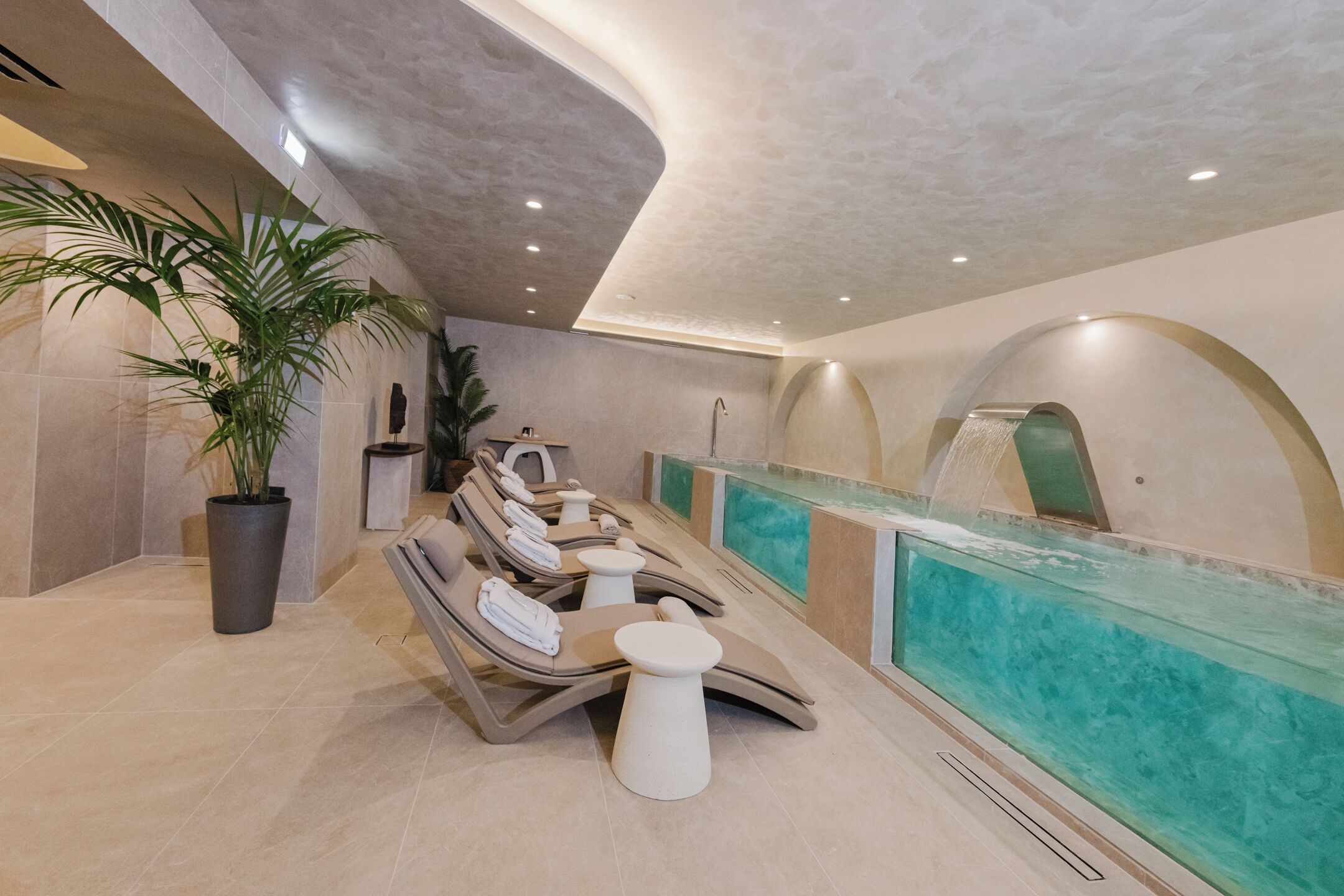 A spa area with a long bench, a small table, and a water feature.