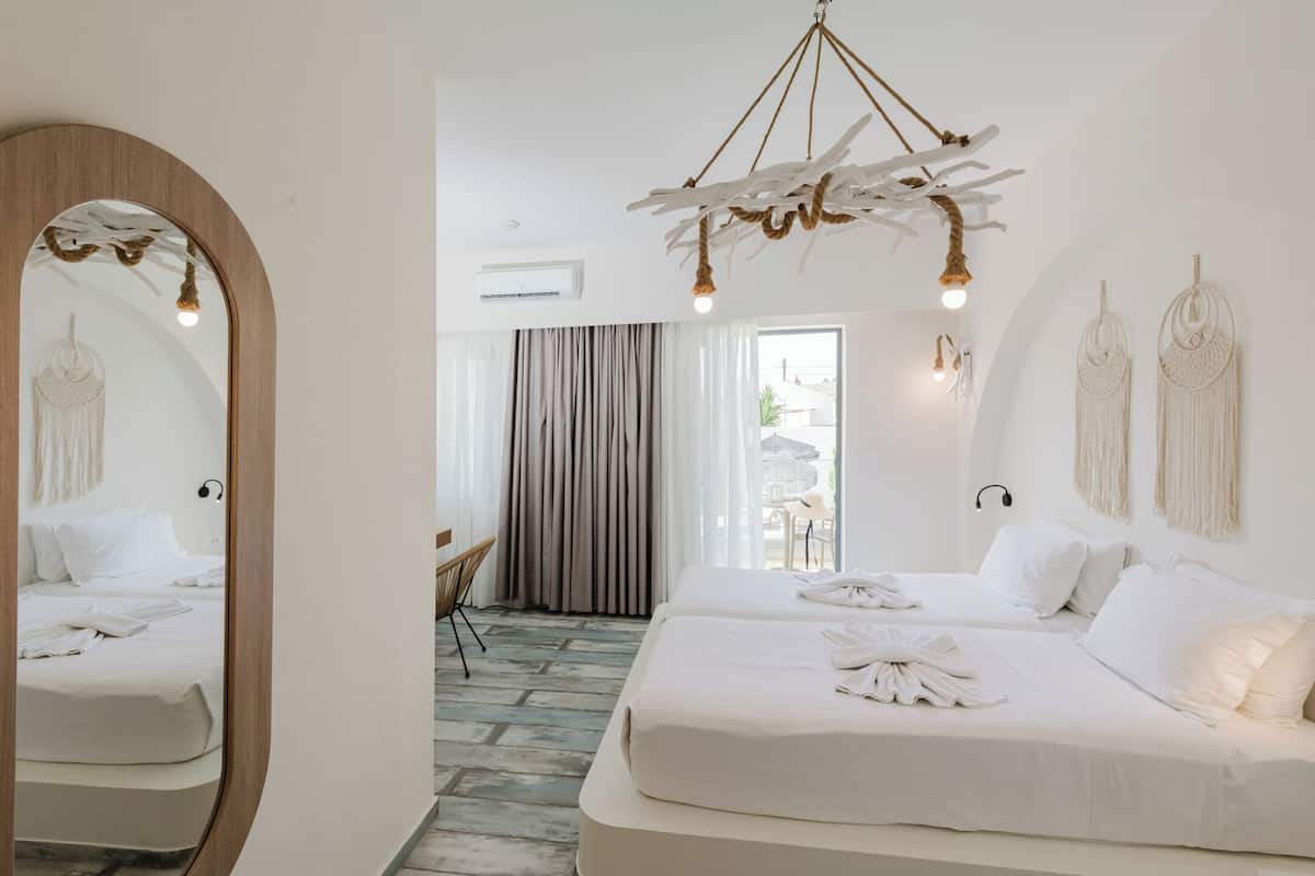 A hotel room with a large bed, a mirror, a hanging light fixture, and a view of the outside.