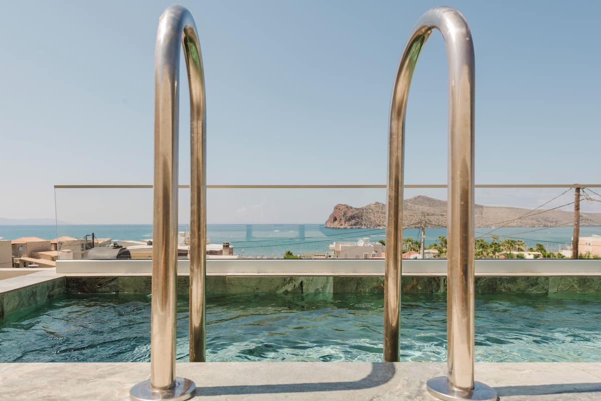 A pool with metal railings and a view of the sea and a bridge in the background.