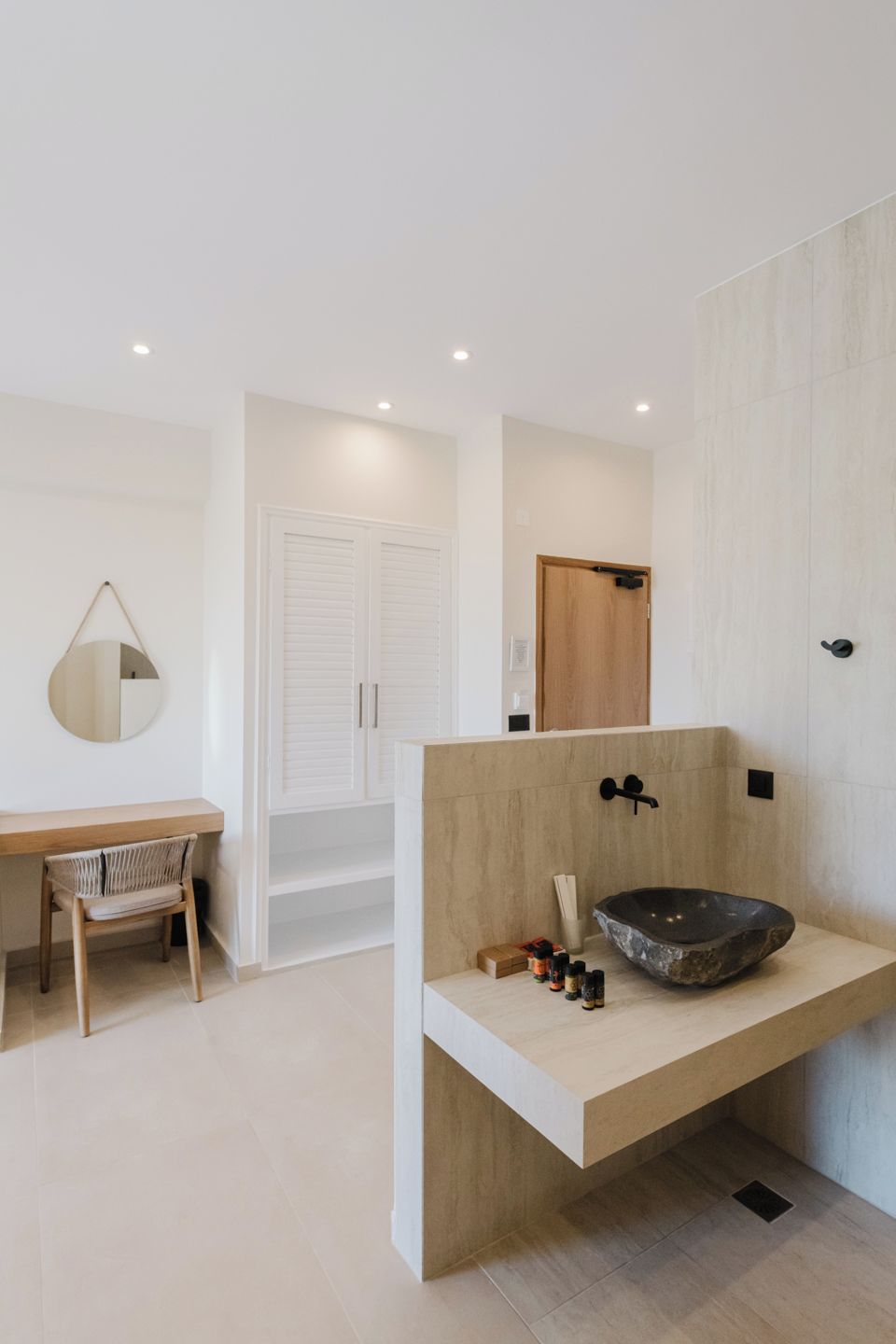 A modern bathroom with a wooden vanity, a large mirror, and a unique stone basin.