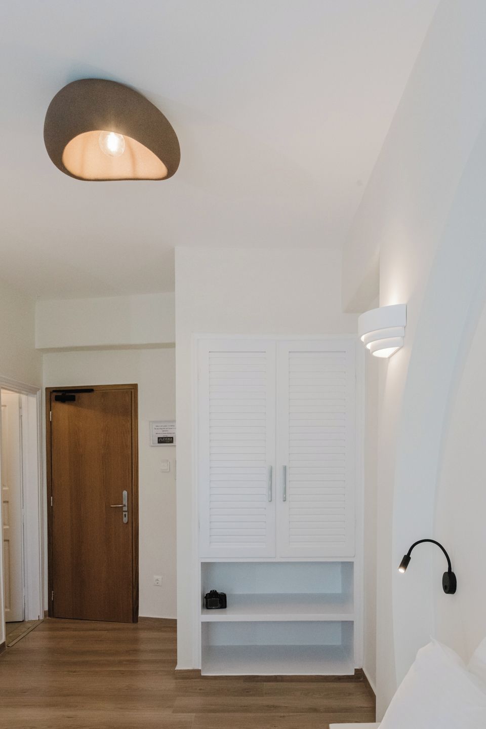Ein modernes Interieur mit Holzboden, einem weißen Kleiderschrank und einer Deckenleuchte.