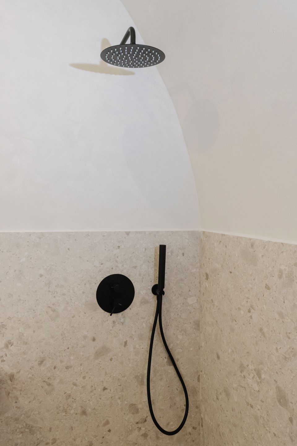 A showerhead and a handheld shower attachment on a wall.