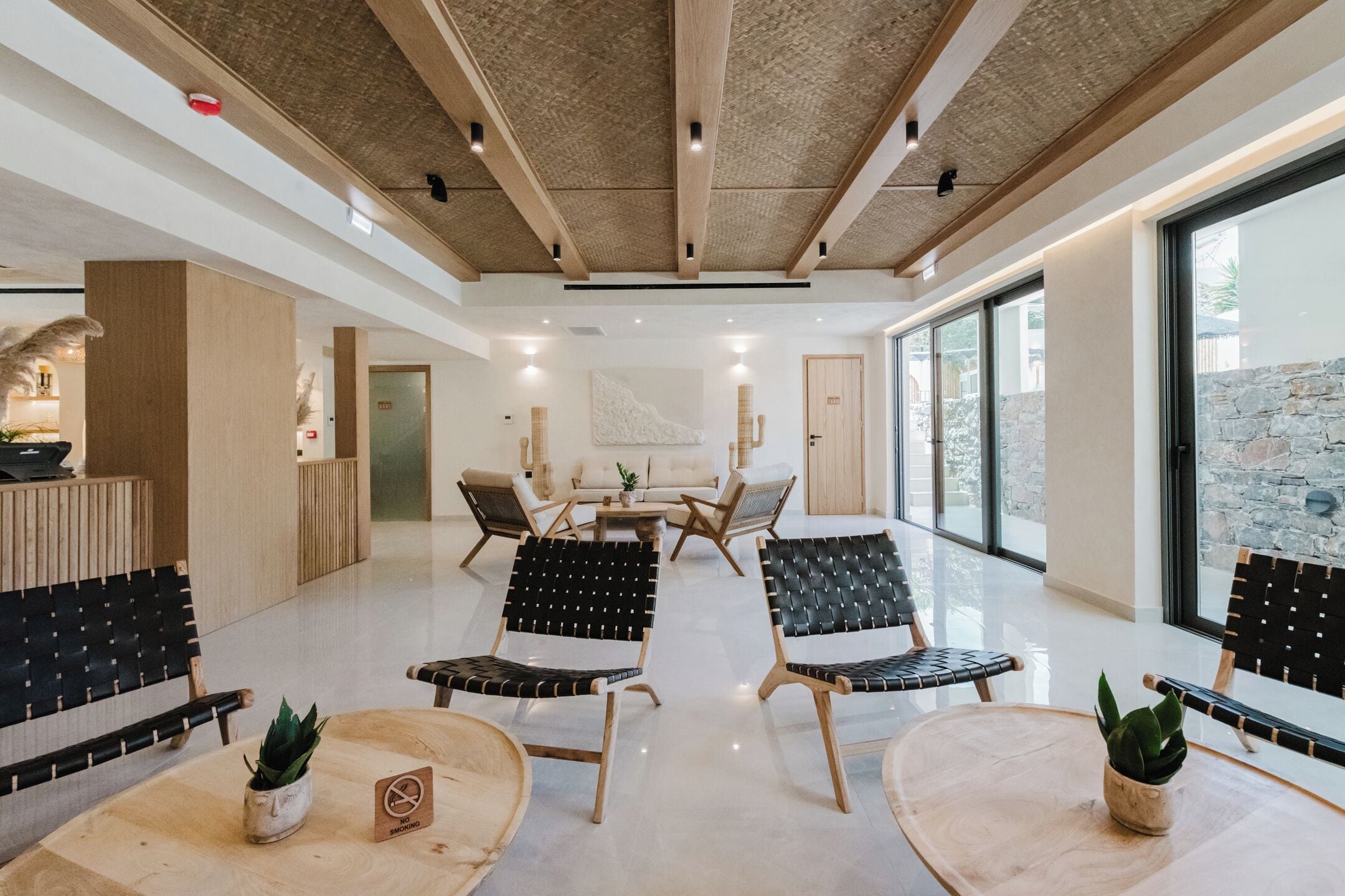 A spacious lobby with a high ceiling, modern furniture, and large windows offering a view of the outdoors.