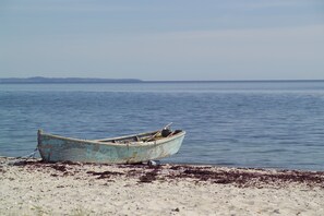 A boat on a sandy beach with calm water in the background. - Norsminde Kro (Odder)