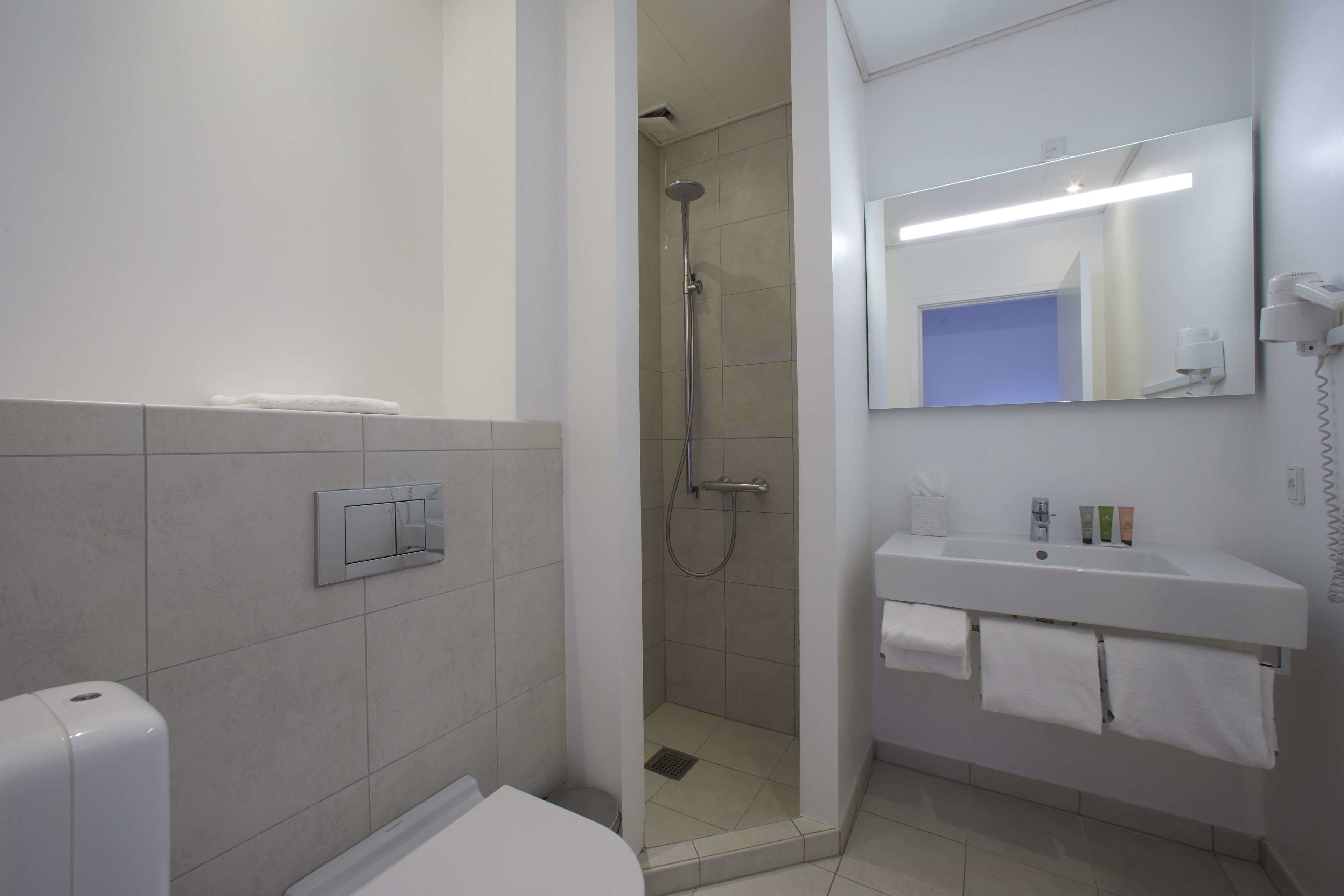 A modern bathroom with a shower, toilet, and sink.
