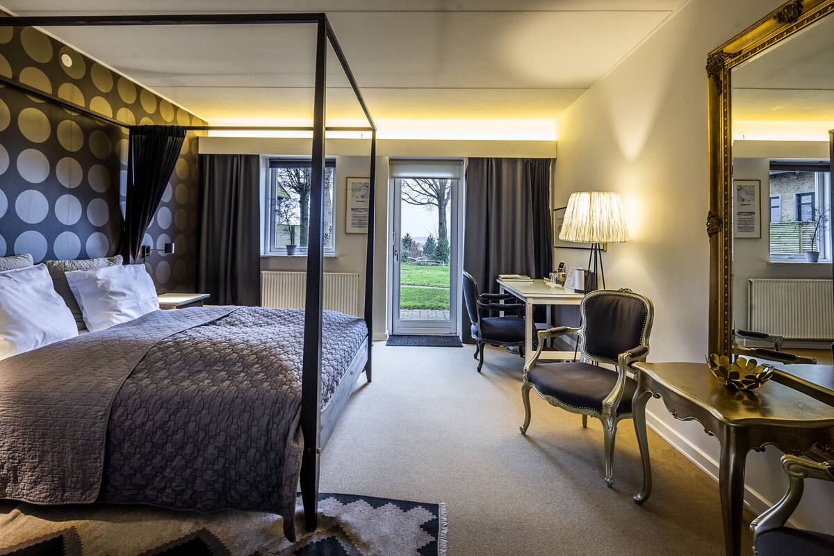 Una habitación de hotel con una cama grande, un escritorio, una silla y un espejo.