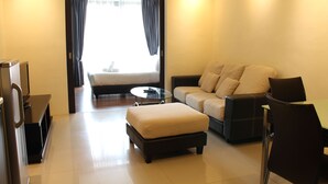 A modern hotel room with a sofa, ottoman, and a glass coffee table. - Grand Service Suite at Times Square (Kuala Lumpur)