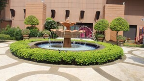 A fountain in a courtyard surrounded by potted plants and a building with a tiled floor. - Grand Service Suite at Times Square (Kuala Lumpur)