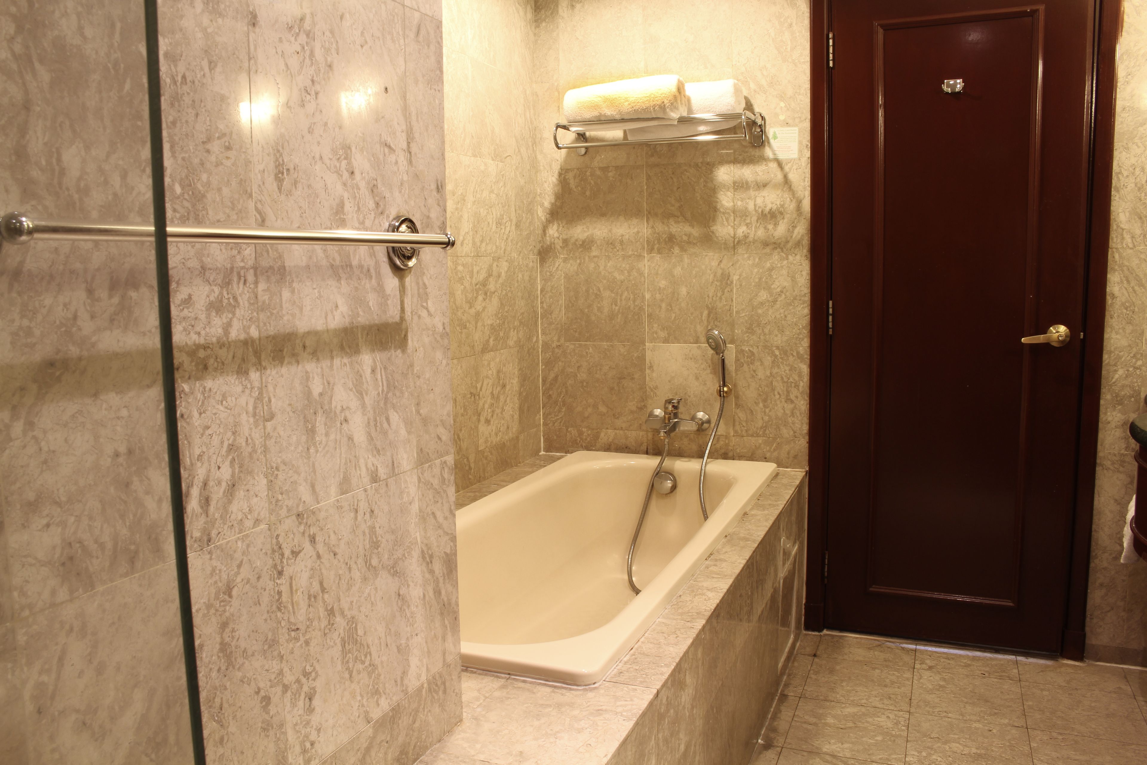Un baño con bañera, cabina de ducha de vidrio y puerta de madera.