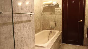 Un baño con bañera, cabina de ducha de vidrio y puerta de madera.