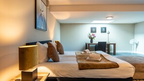 A hotel room with a neatly made bed, a bedside lamp, a small table with a vase of flowers, and a chair. - Najade Resort (Loosdrecht)