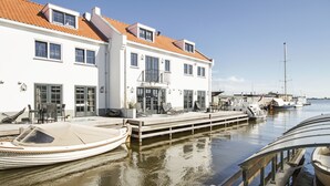 A waterfront property with a dock, a boat, and a building with multiple windows and balconies. - Najade Resort (Loosdrecht)