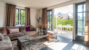 A spacious living room with a sofa, coffee table, and a dining area with a table and chairs. - Najade Resort (Loosdrecht)