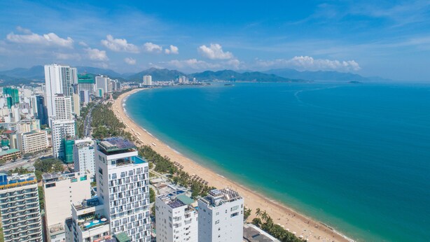 A coastal cityscape with high-rise buildings, a sandy beach, and a clear blue sea. - Pavillon Garden Hotel & Spa (Nha Trang)