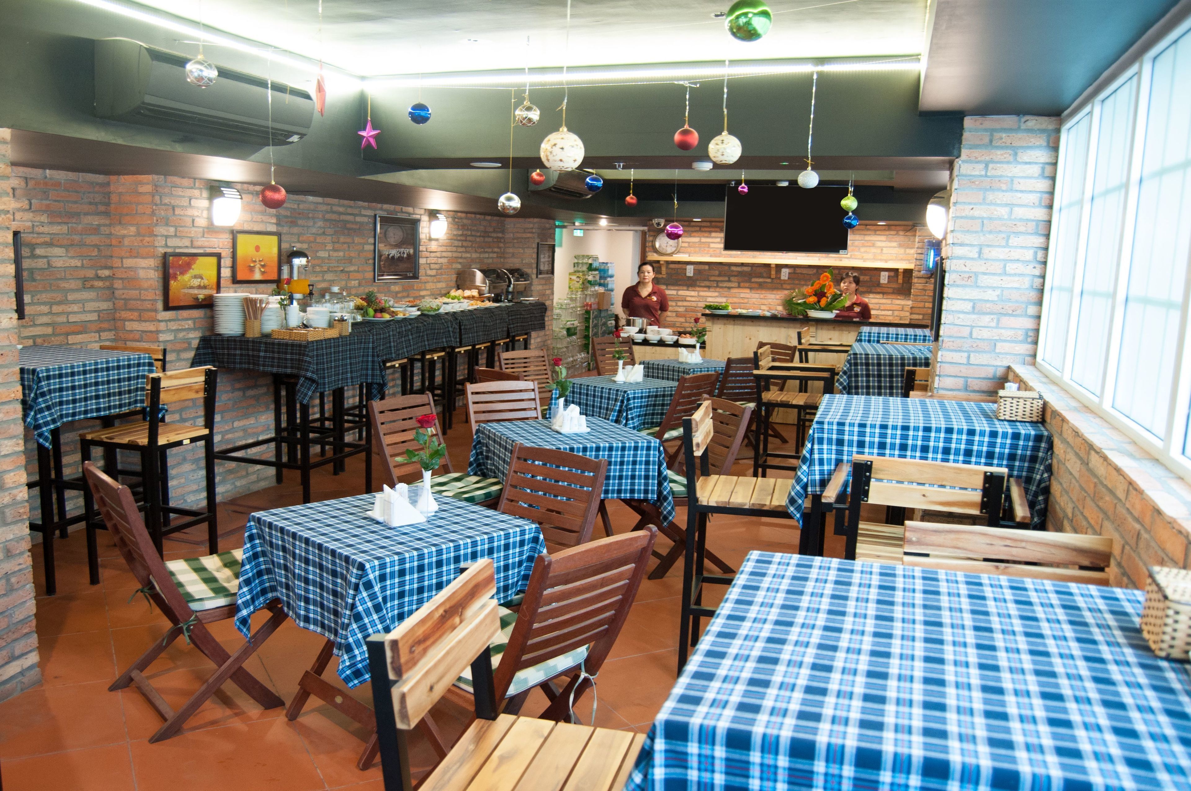 Un restaurante con paredes de ladrillo, mesas con manteles a cuadros azules y decoraciones colgantes.