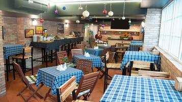 Un restaurante con paredes de ladrillo, mesas con manteles a cuadros azules y decoraciones colgantes.