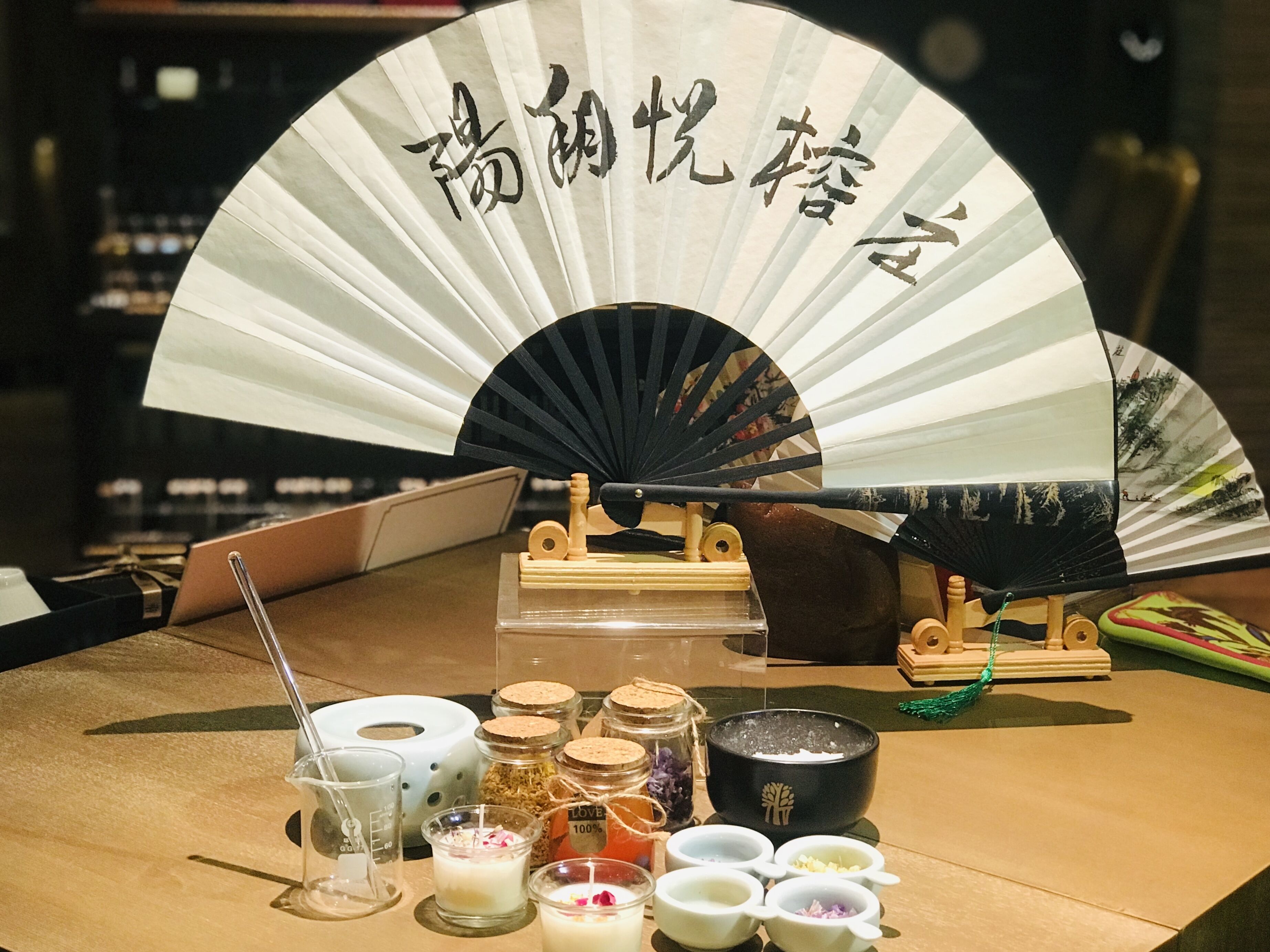 A table with a fan, candles, and various jars and bowls, likely for a tea ceremony or similar event.