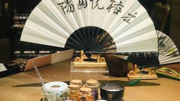 A table with a fan, candles, and various jars and bowls, likely for a tea ceremony or similar event.