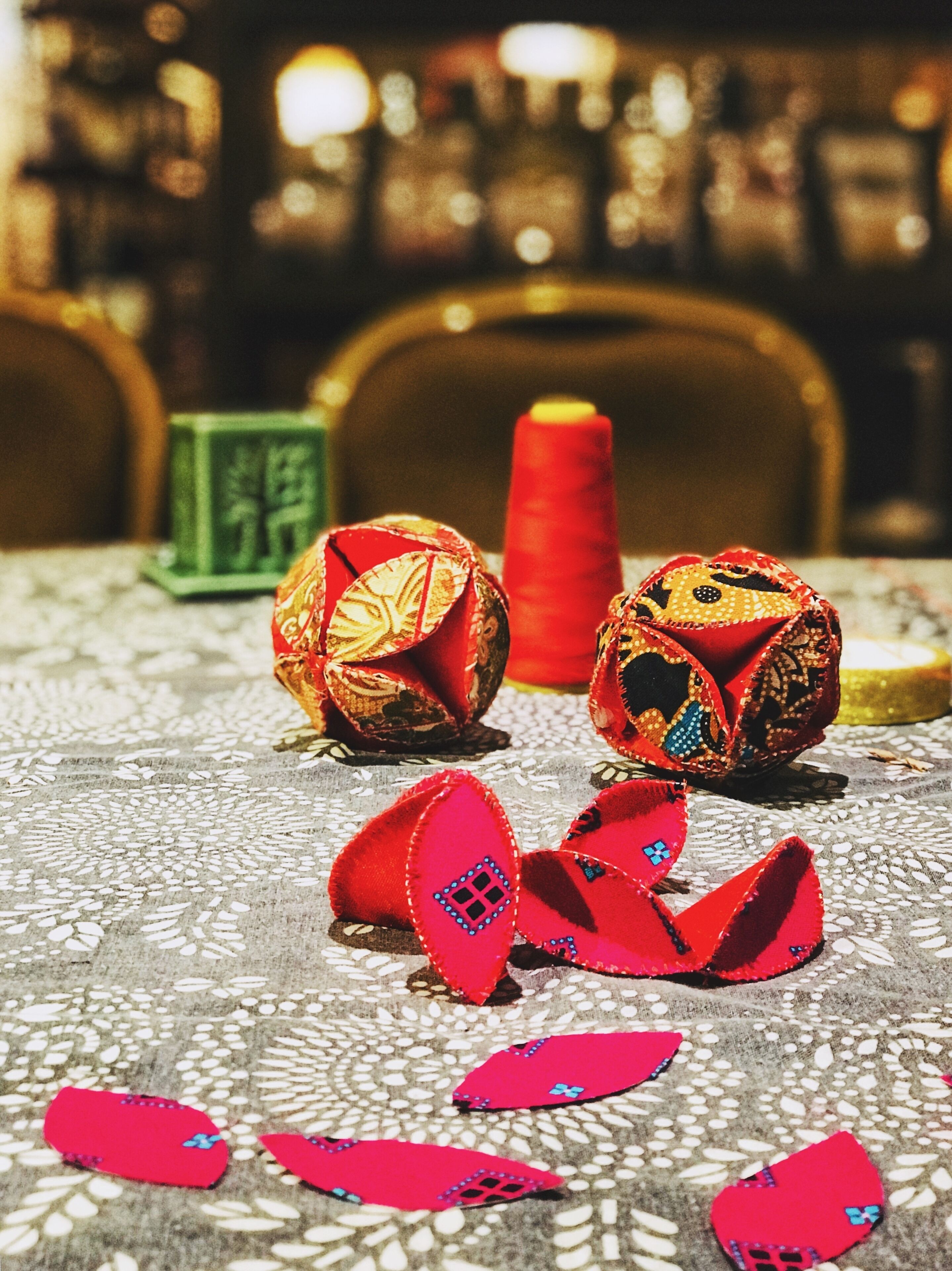 A table with decorative items, including two intricately designed fabric balls and a red candle.