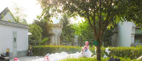 A courtyard with a tree, a building, and children playing in foam.