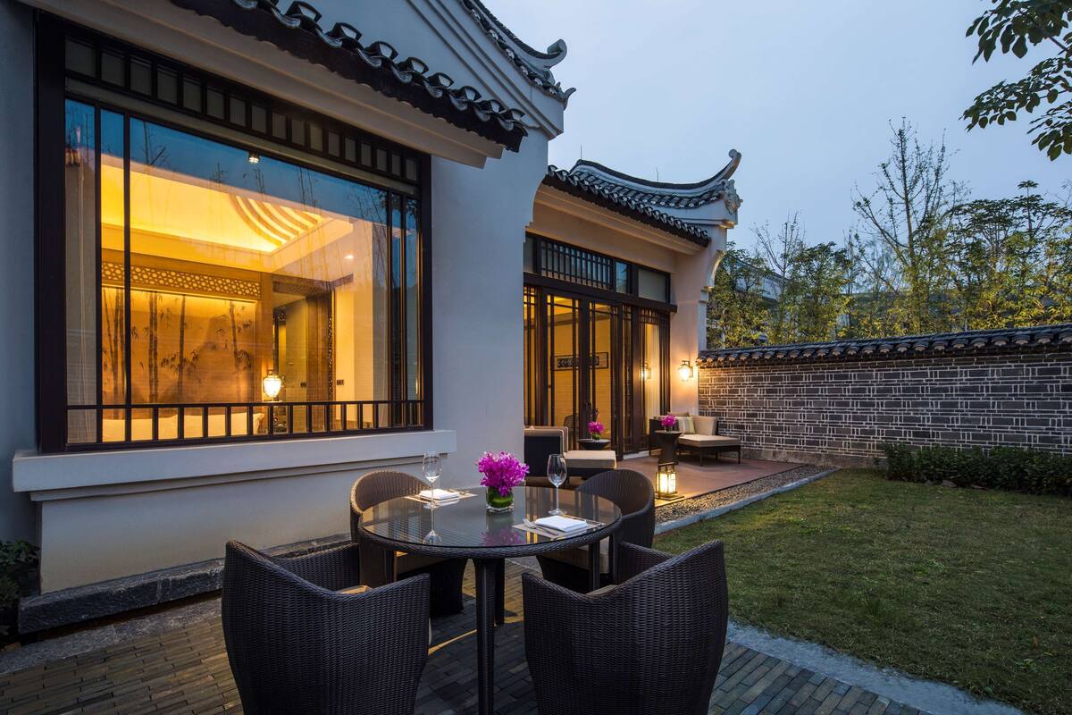 A traditional Chinese-style building with a patio area featuring wicker furniture and a glass table.