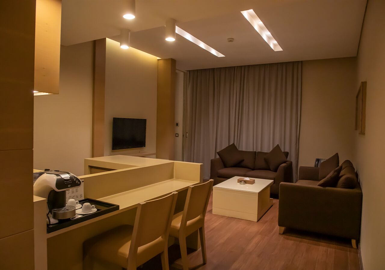 Una habitación de hotel moderna con comedor, sofá y televisor.