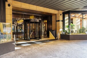 A hotel entrance with a revolving door, a tiled floor, and a glass facade.