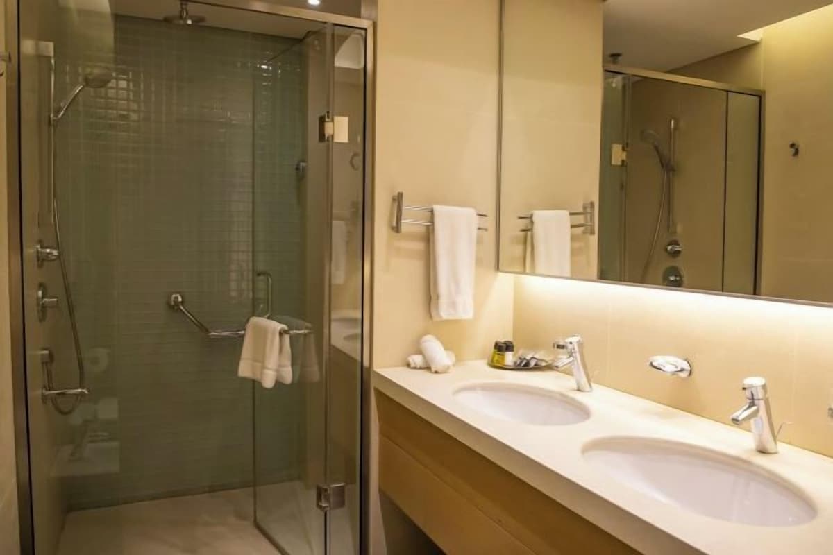 A modern bathroom with a glass-enclosed shower, two sinks, and a large mirror.