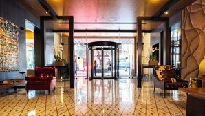 A lobby with a tiled floor, a revolving door, and a red armchair. - Saifi Suites Hotel (Beirut)