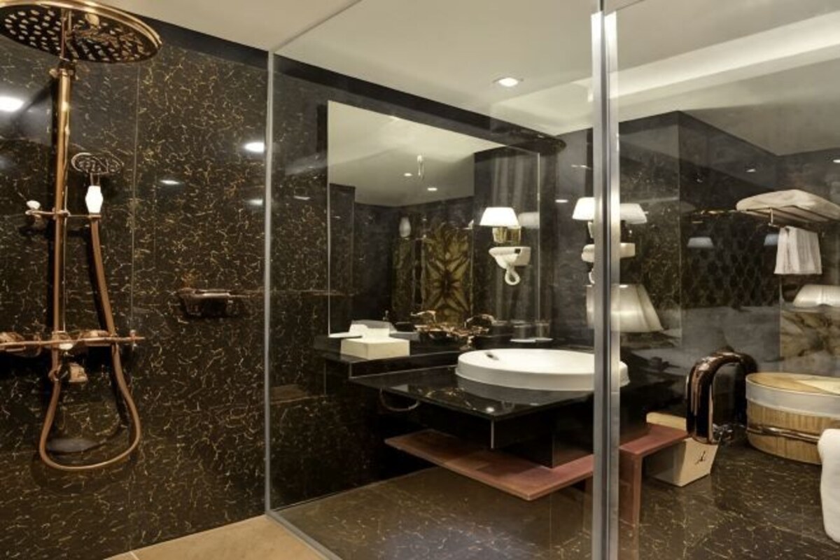 Un baño moderno con ducha de vidrio, un espejo grande y tocador con lavamanos.