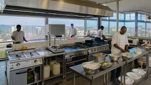 Uma cozinha moderna com eletrodomésticos de aço inoxidável, amplas janelas e vista para o horizonte da cidade.