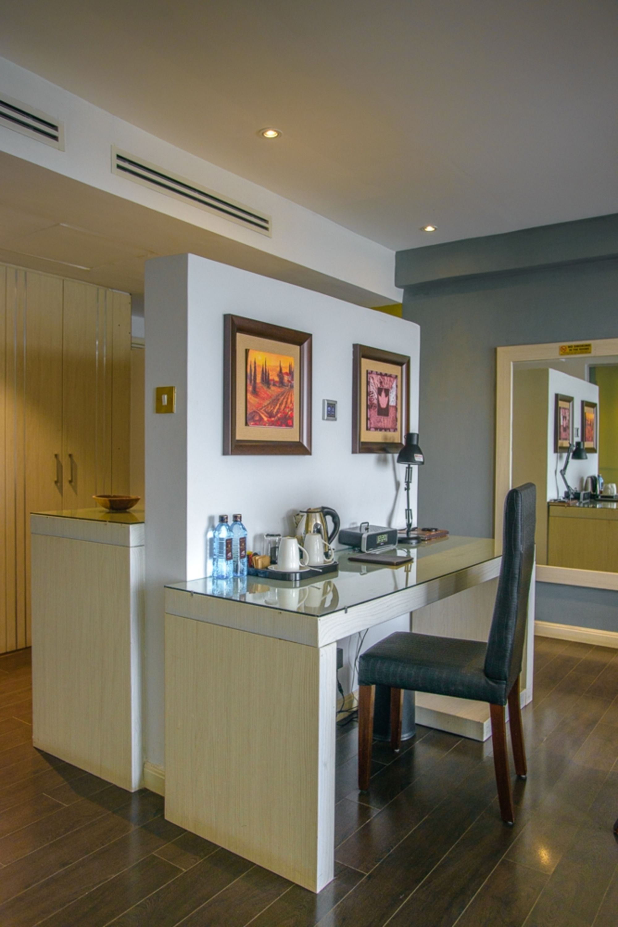 A modern kitchen with a central island, wooden cabinets, and framed artwork on the walls.