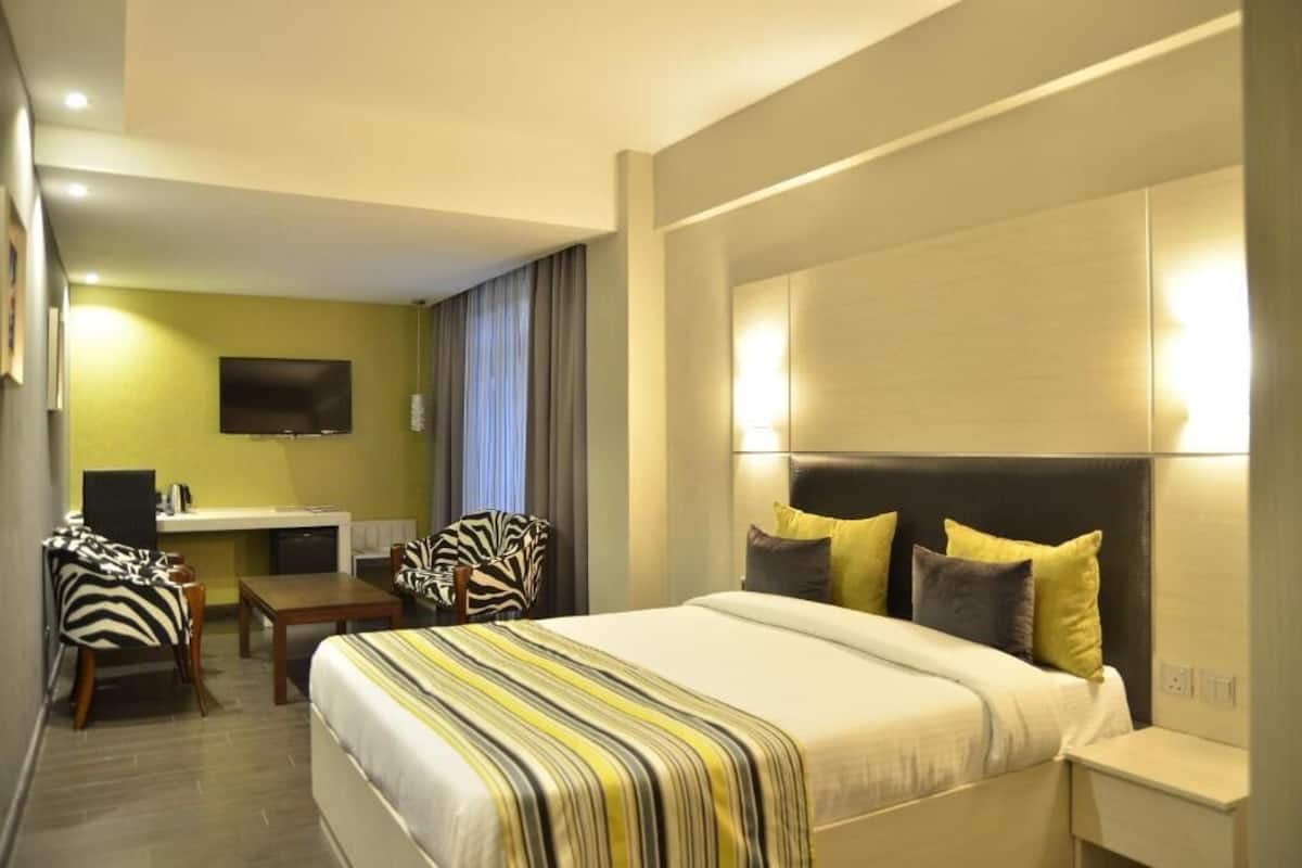 A hotel room with a bed, a desk, a chair, and a television.