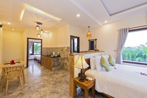 Habitación de hotel con cama, mesita de noche, lámpara y vistas a zonas verdes.