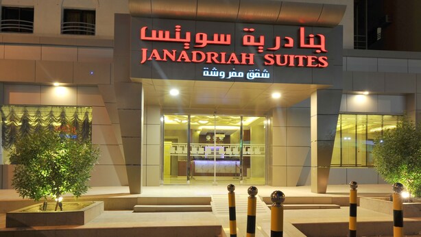 L’extérieur de l’établissement Janadriyah Suites présente un design moderne, avec une entrée imposante et une façade bien éclairée.