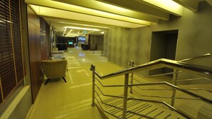 Un hall d’hôtel comprenant un comptoir d’accueil, un espace salon et un escalier.