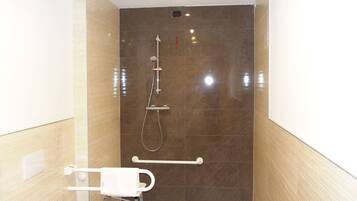 Un baño moderno con ducha a nivel, barra de apoyo y perchero.