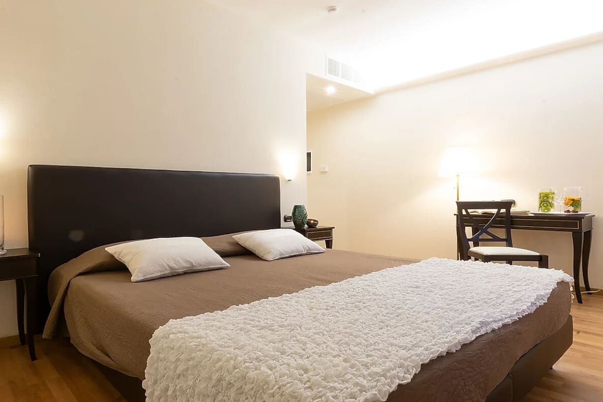 A bedroom with a bed, bedside tables, a desk, and a chair.