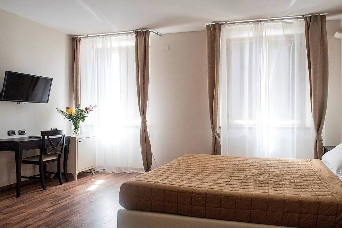 A hotel room with a bed, a desk, and a television.