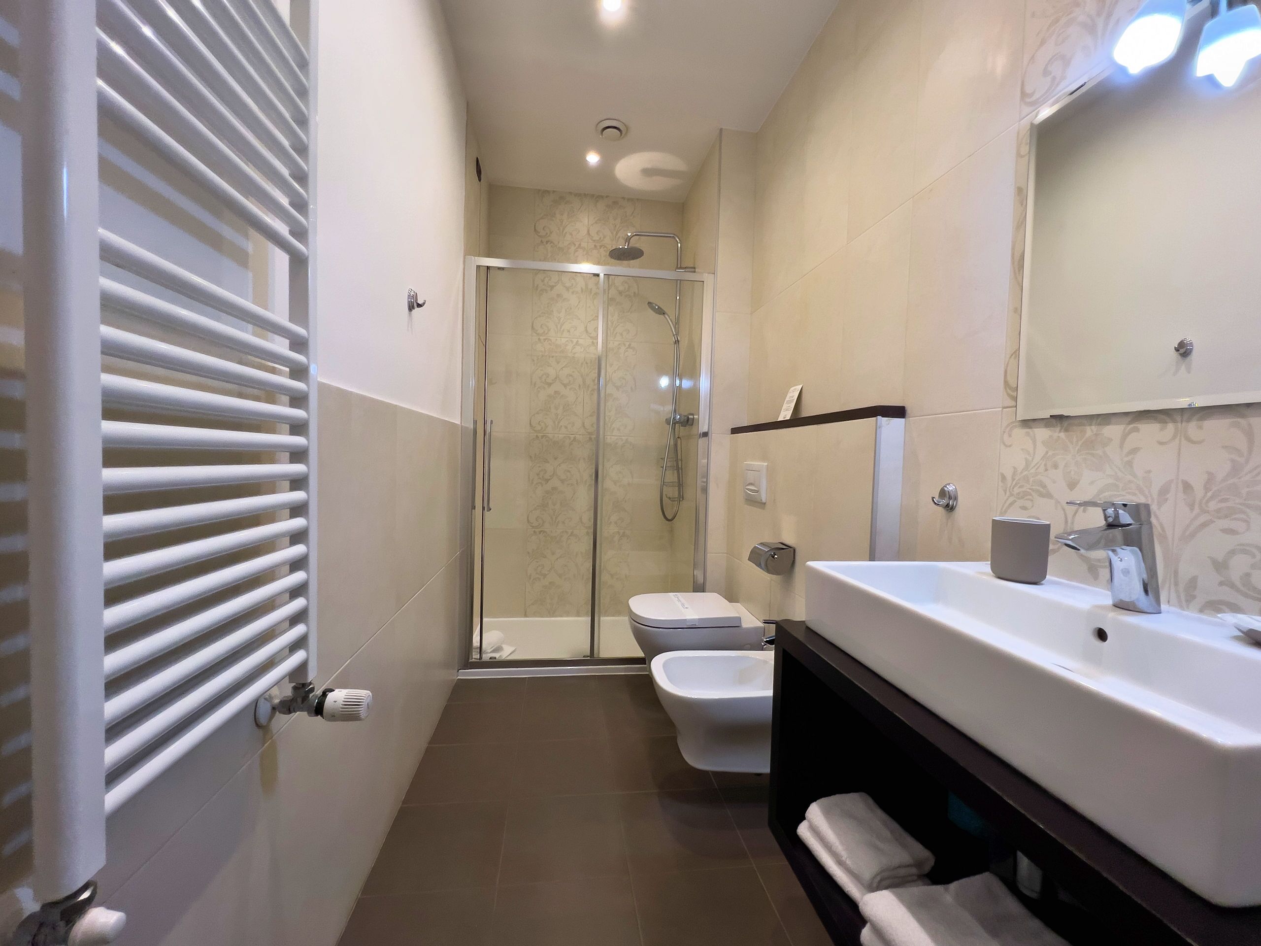A modern bathroom with a glass-enclosed shower, a white toilet, and a vanity with a mirror.