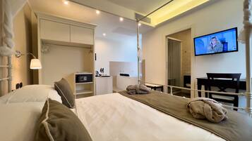 Una habitación de hotel con cama, escritorio, silla, televisor y armario.