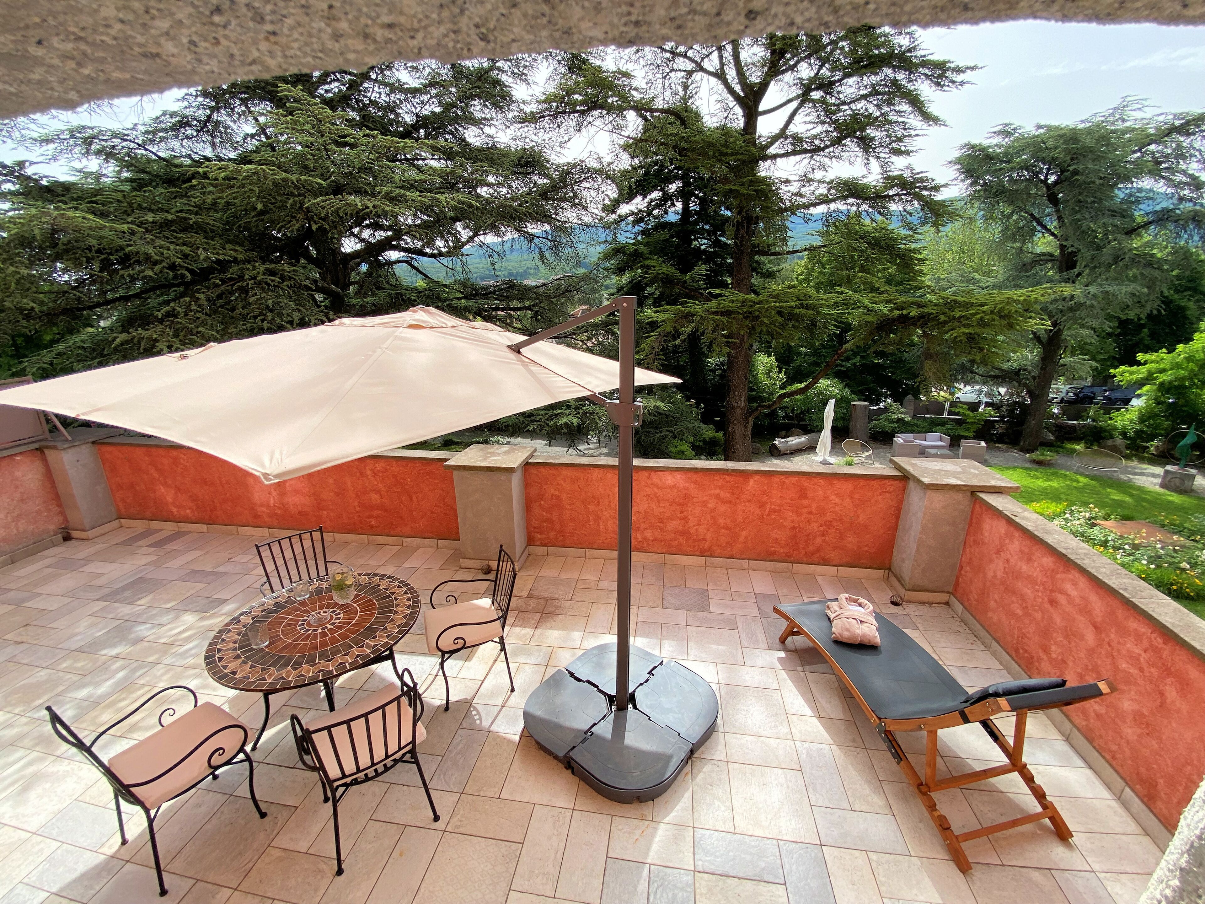 A patio with a table, chairs, an umbrella, and a lounge chair.