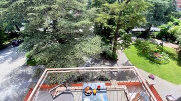 Una terraza con una mesa, sillas y vistas a un jardín exuberante y árboles.