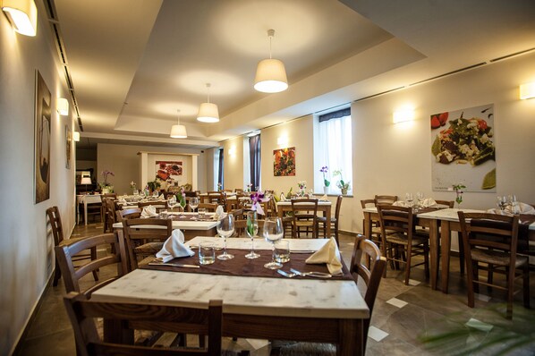 A restaurant with multiple dining tables, chairs, and pendant lights. - Grand Hotel Impero - Wellness & Exclusive SPA (Castel del Piano)